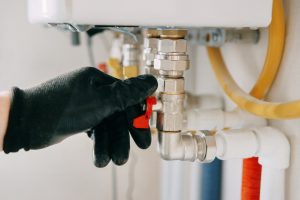 Close-up of a technician’s gloved hand turning a boiler valve during a heating system adjustment.
