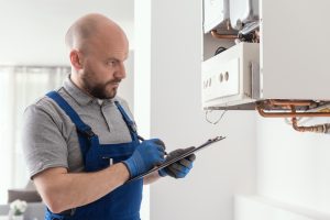 Gas Safe engineer carrying out a boiler safety inspection and completing landlord gas safety certificate paperwork