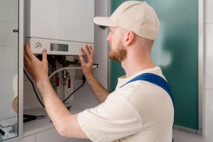Gas Safe engineer installing and adjusting a wall mounted system boiler in a UK home